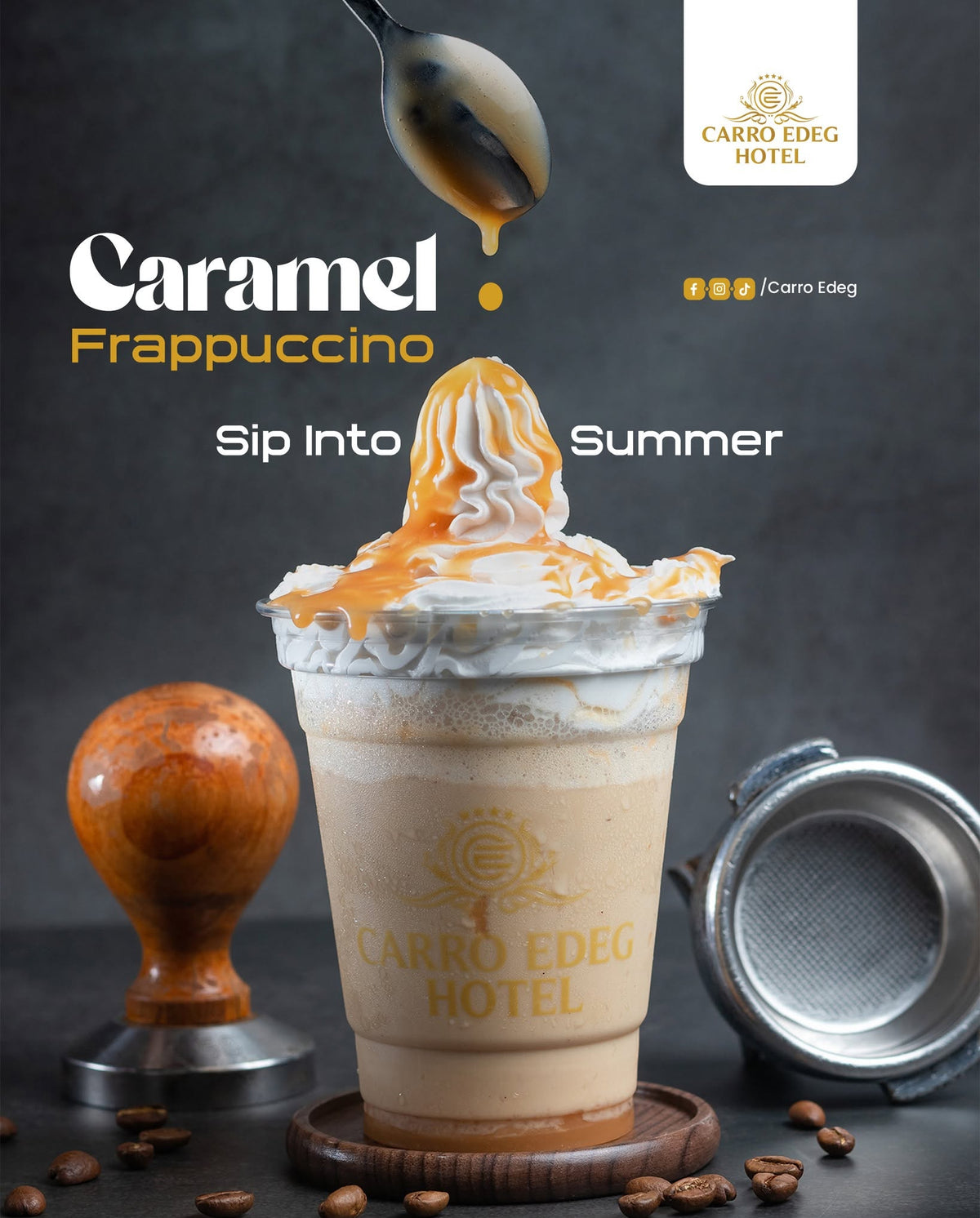 A branded promotional photo of a Carro Edeg Hotel Caramel Frappuccino. A tall frosted cup filled with a light caramel drink sits on a coaster, topped with whipped cream and drizzled caramel syrup.