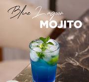 A blue and white mojito cocktail in a clear glass with ice, mint leaves, and lime slices, set on a dark marble table with promotional text overlays including 'Blue Lagoon Mojito', a '2 Anniversary' badge, and a 'Discount 30% OFF' sticker.