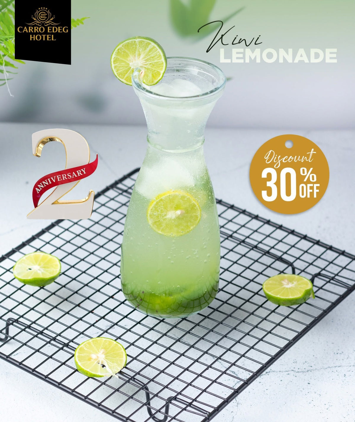 A glass carafe filled with a light green iced beverage and lime slices, placed on a black wire cooling rack. The scene includes lime wedges on a light surface, promotional text reading 'Kivi Lemonade,' a 'Carro Edeg Hotel' logo, a '2 Anniversary' badge, and a 'Discount 30% Off' tag.