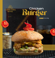 Promotional graphic for a Carro Edeg Hotel Chicken Burger, featuring a close-up of a gourmet burger on a black wire rack with tomato slices and a cocktail glass in the background.